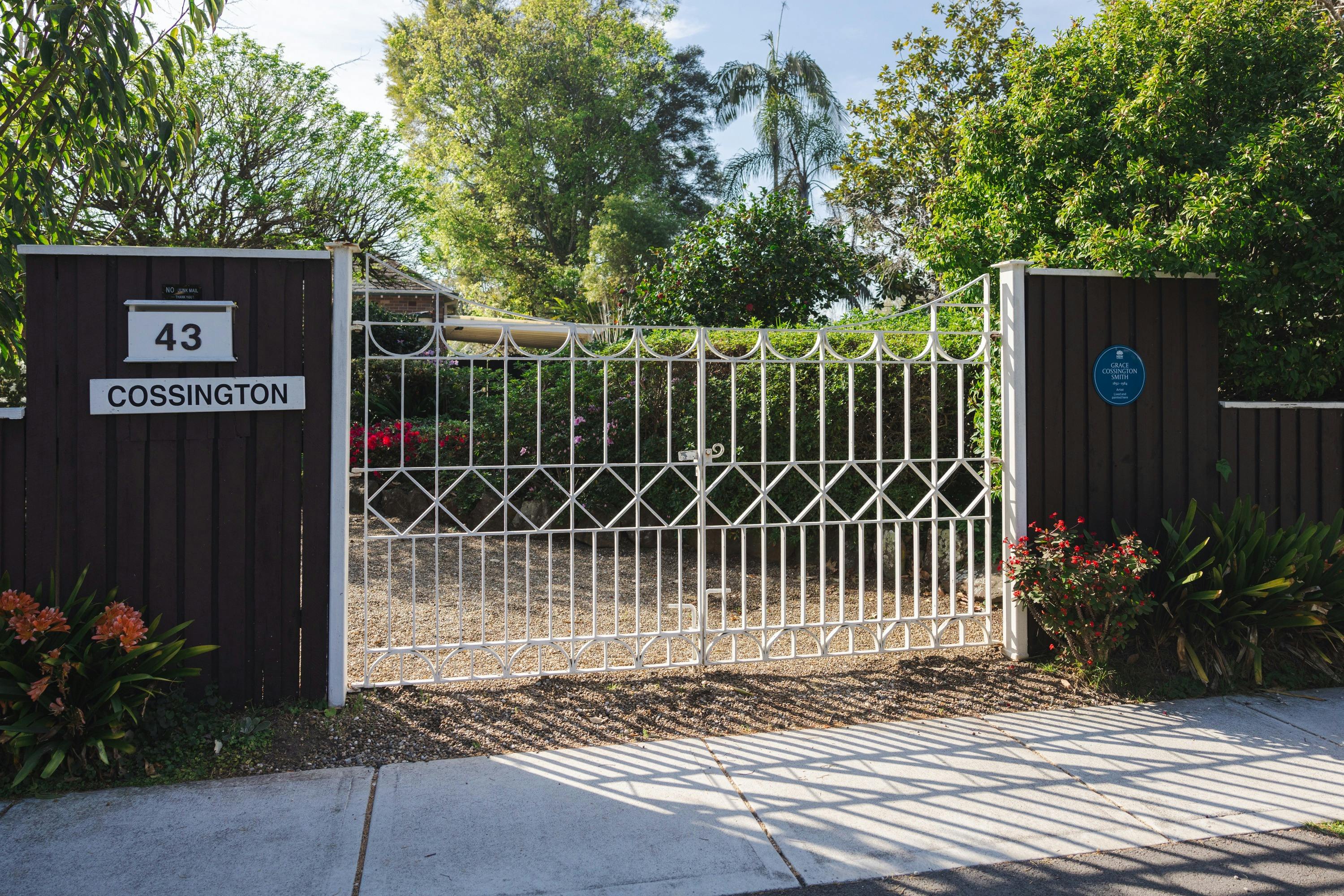 blue plaque on fence next to white metal driveway gate, and sign saying "43" "Cossington"