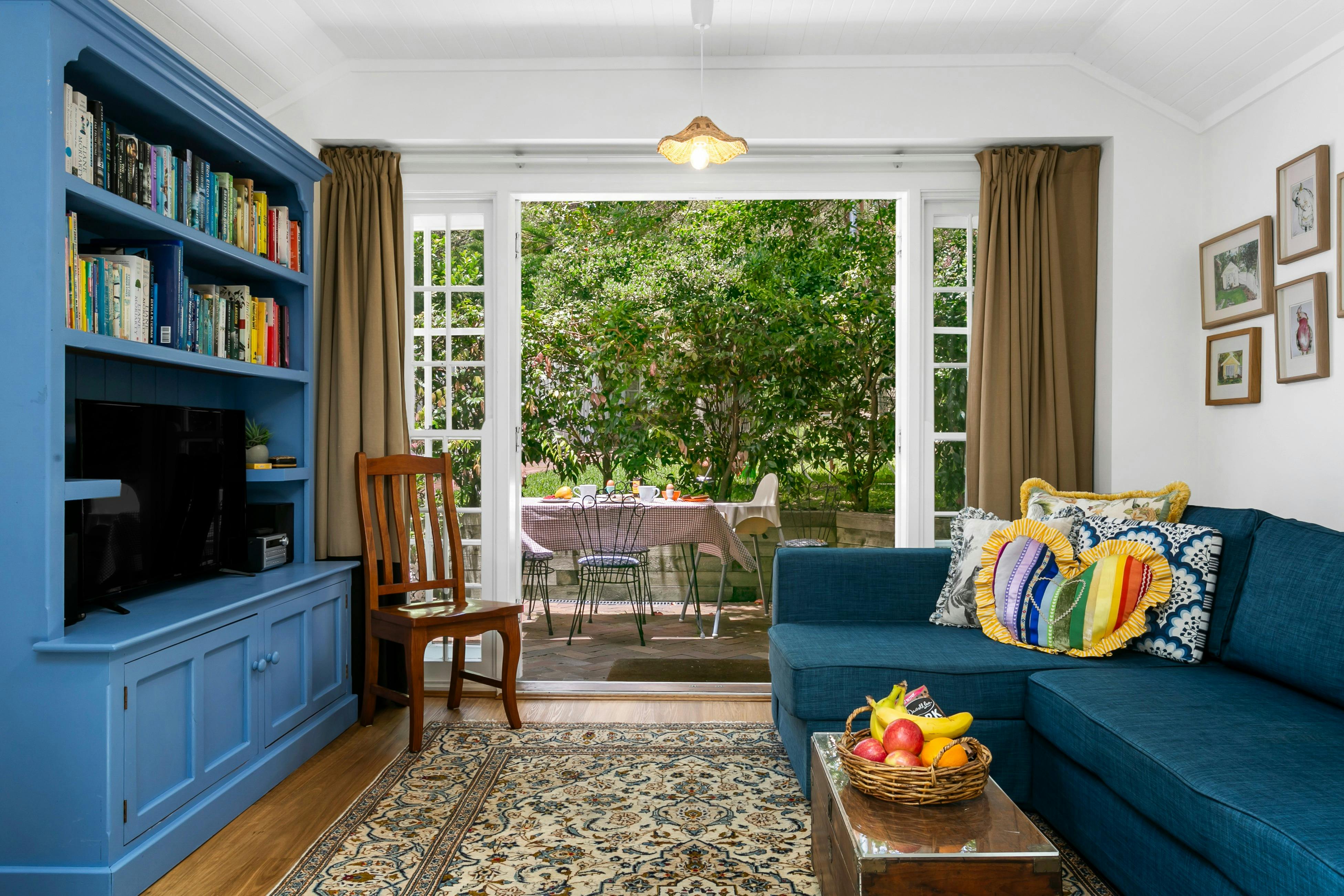 ソファベッド、スマートテレビ、天井ファンを備えたリビングルーム。中庭に面しています。