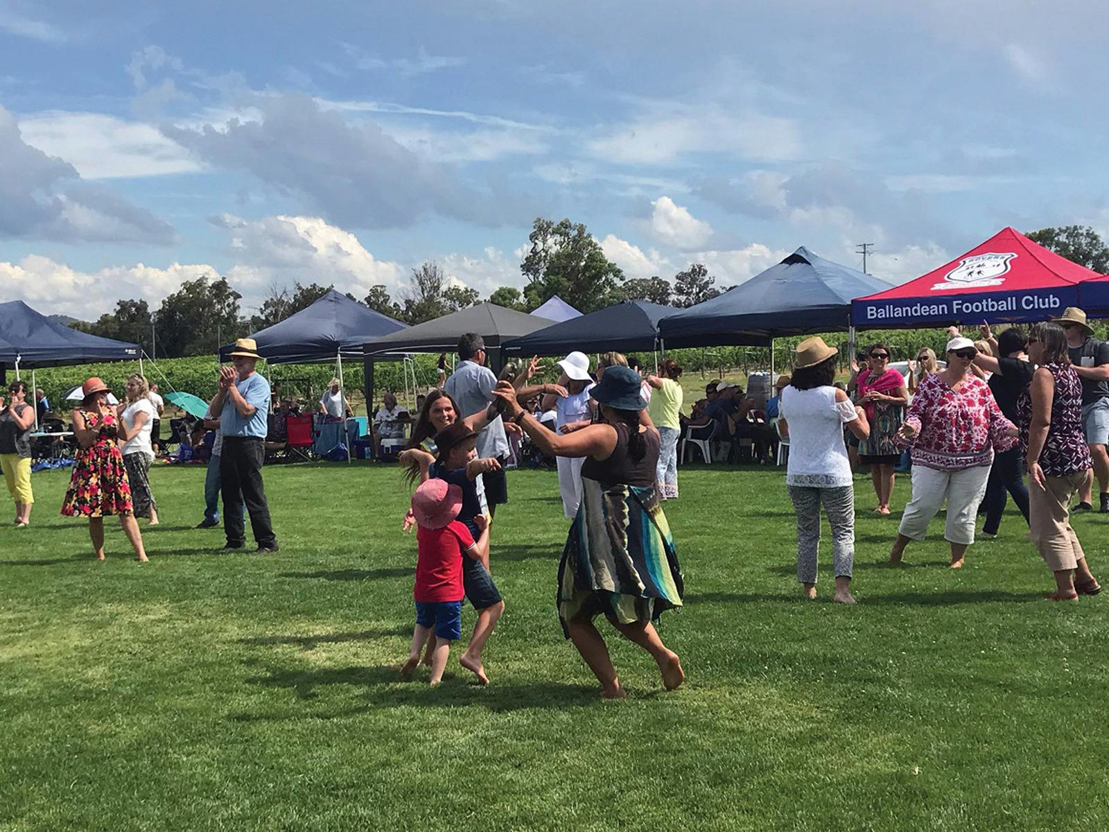 Patrons dancing on the grass with marquees in the background