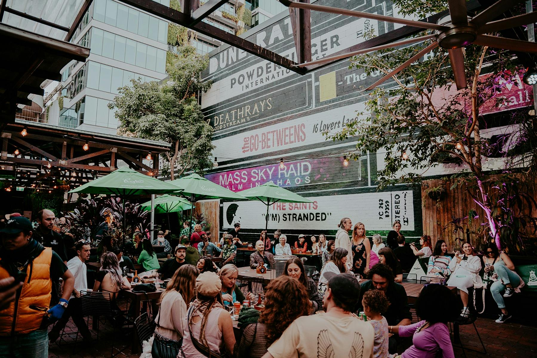 A crowd sitting in The Triffid garden with the hero wall in the background.