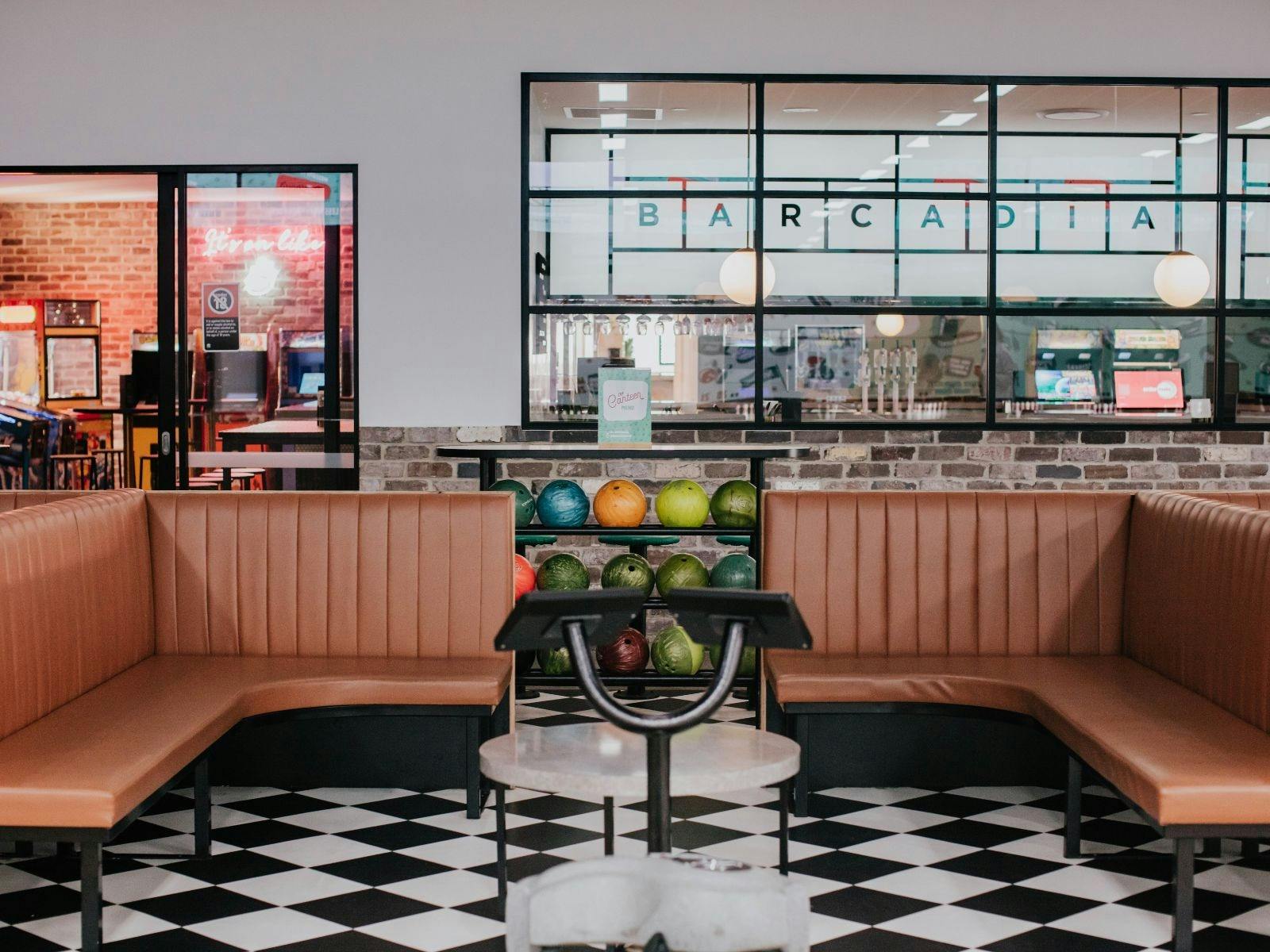 Brown seats with bowling balls behind them on a shelf.