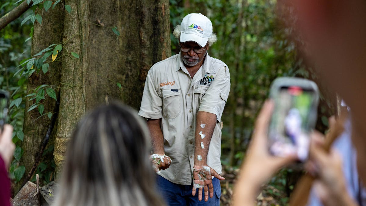 Kuku Yalanji Tribe Member demonstrating to visitors the use of local herbs while a guest photographs