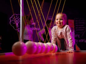 Young girl playing with giant Newtons Cradle in the Sciencentre