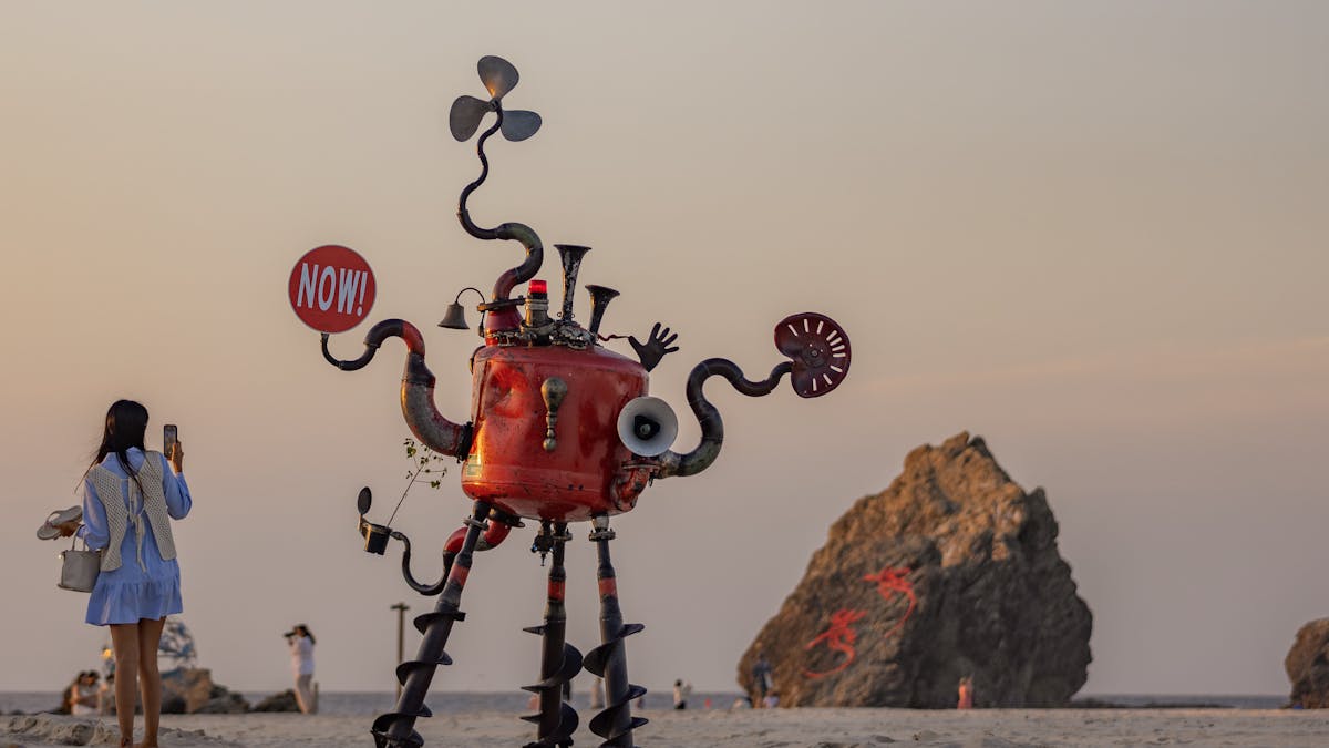 Person taking a picture of a large-scale sculpture on the beach
