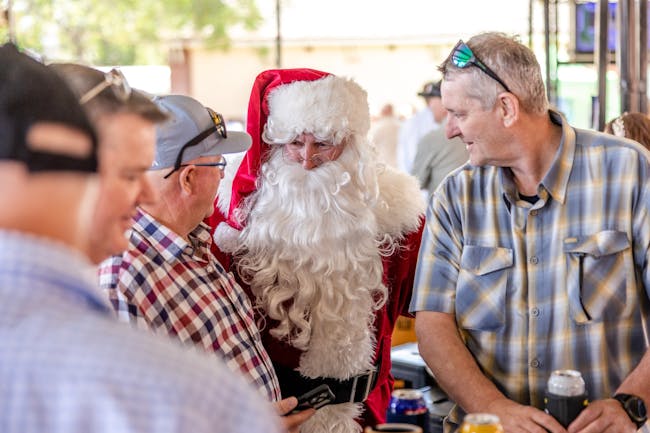 Two men speaking with Santa at a race day