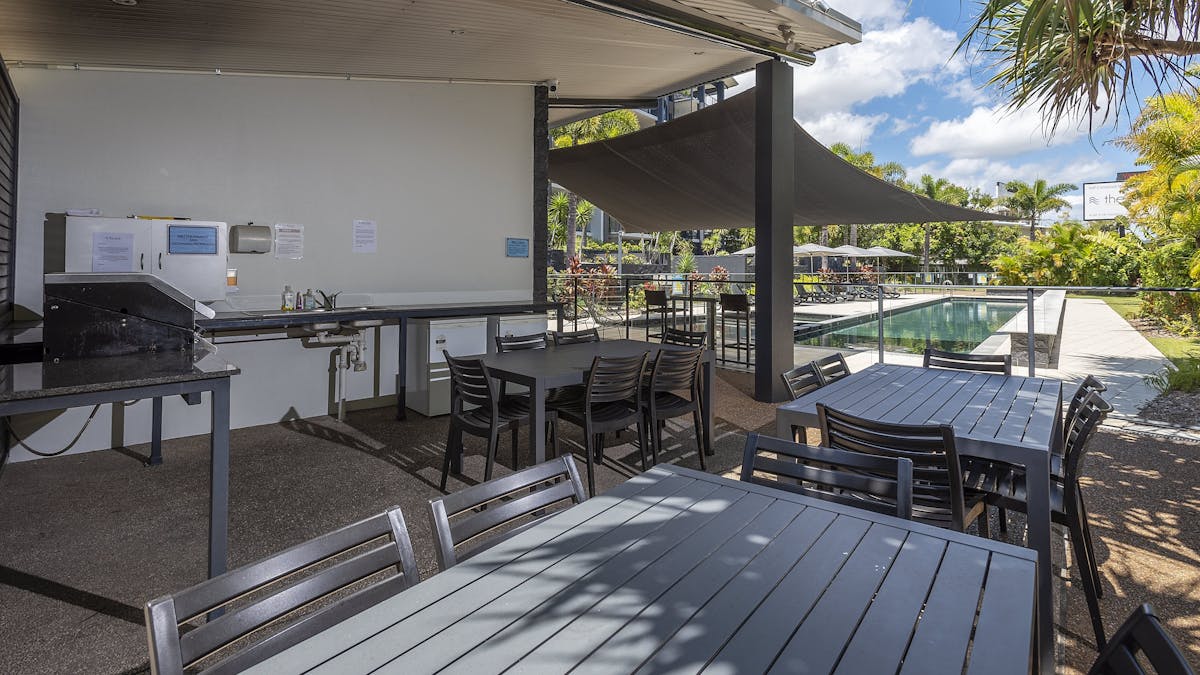 The BBQ area with tables and looking towards the pool at The Bay Apartments Hervey Bay