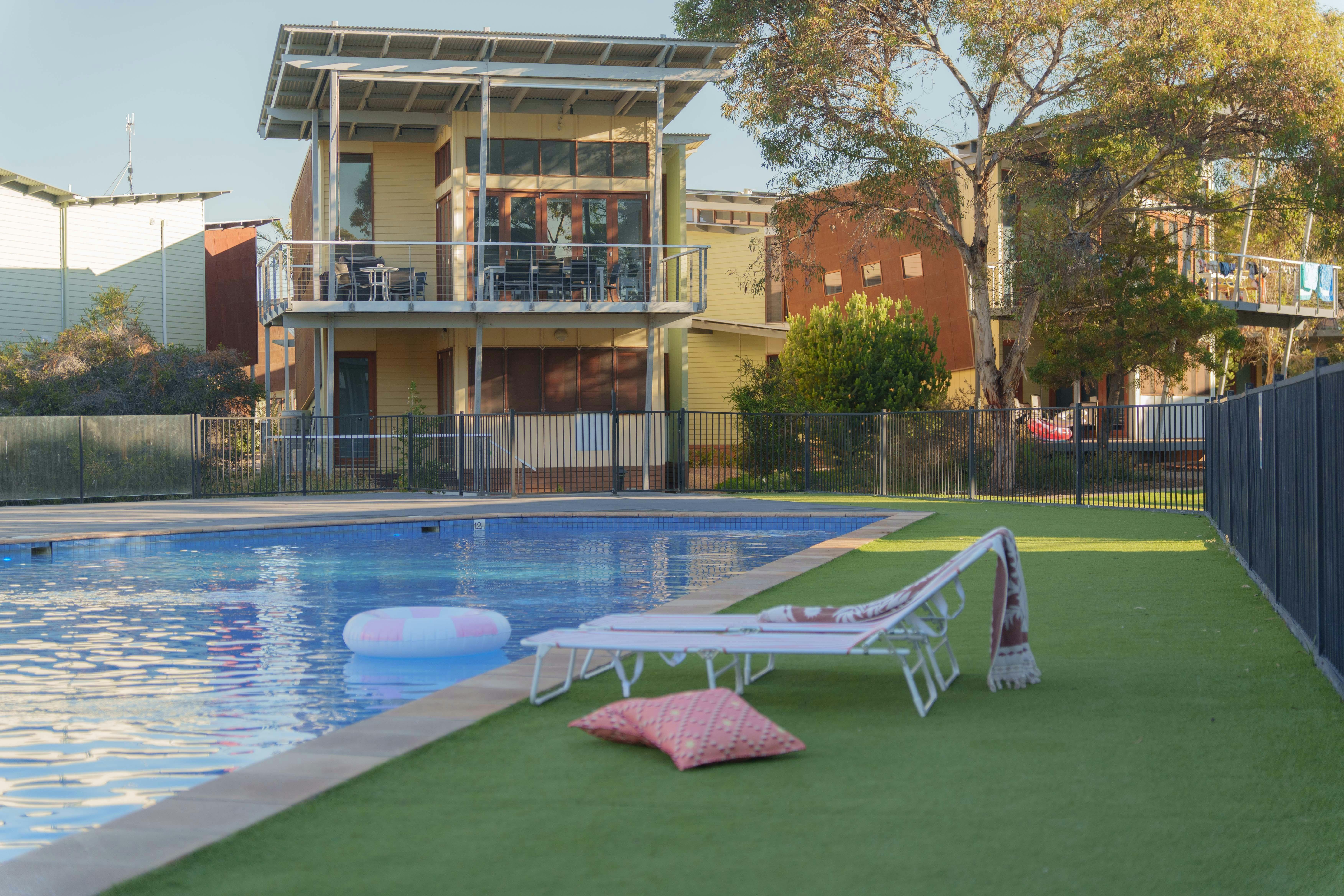 Large swimming pool with a villa in the background - only meters from The Shores villas