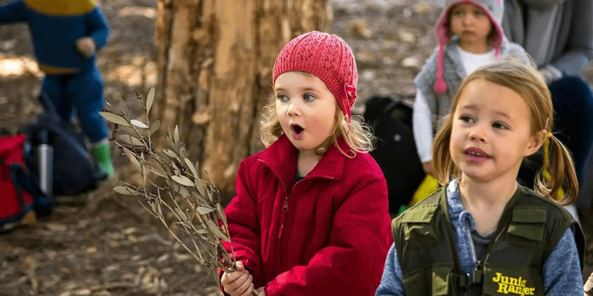 Small child wearing red beanie outside looking surprised or excited