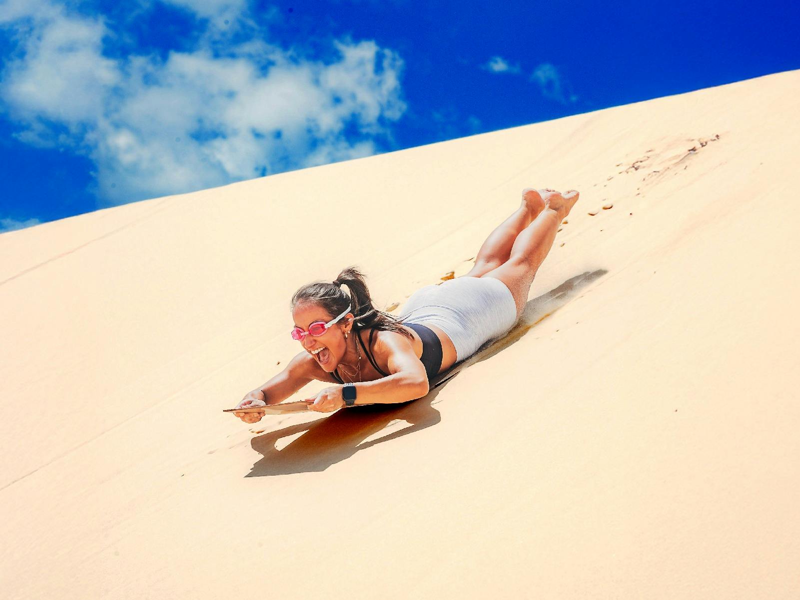 Women sand tobogganing down a sand dune