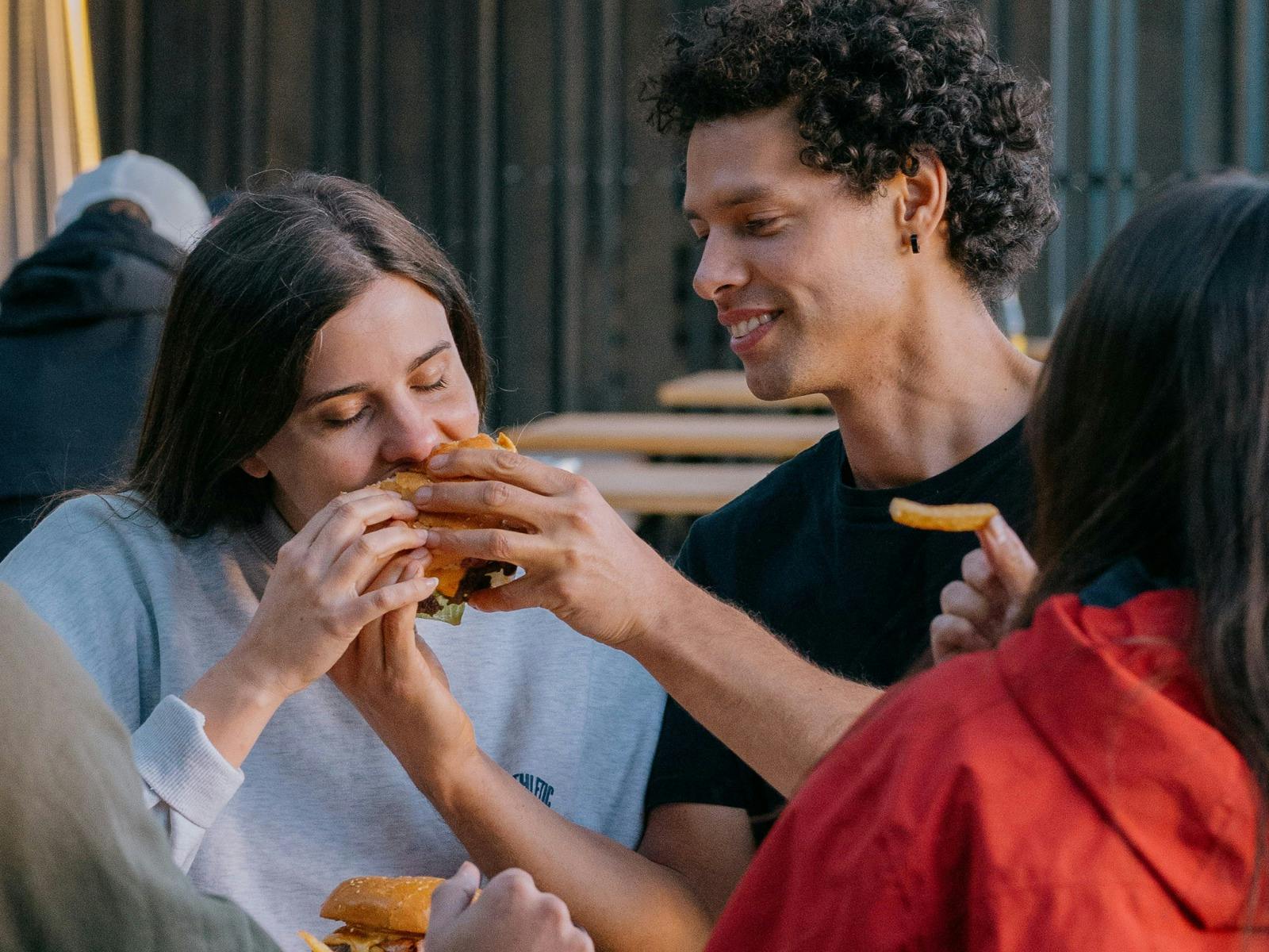 Friends sharing a burger outdoors at Easy Tiger in St Helens.