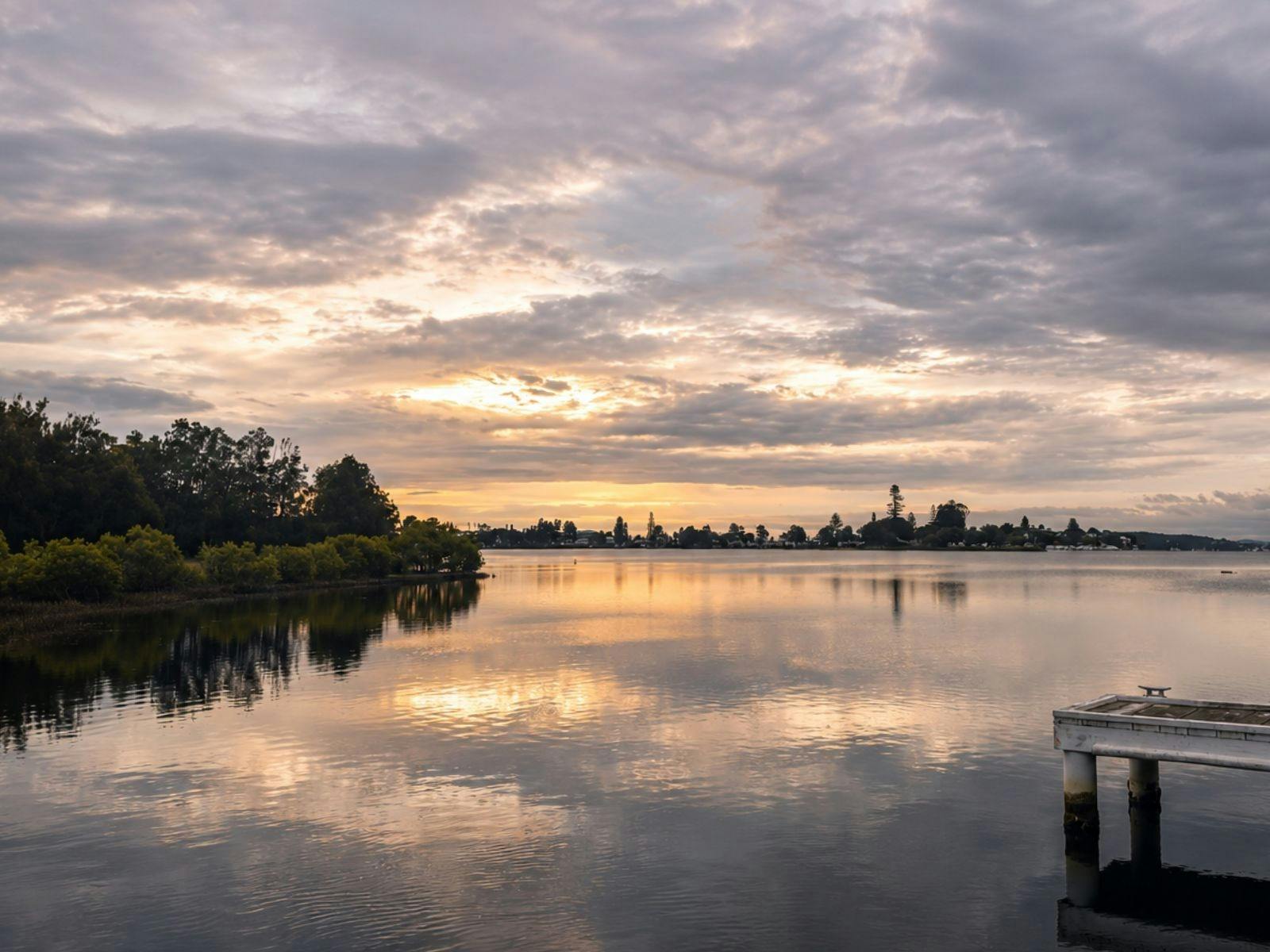 Golden sunset colours reflected across the calm waters of Lake Macquarie, creating a peaceful waterf