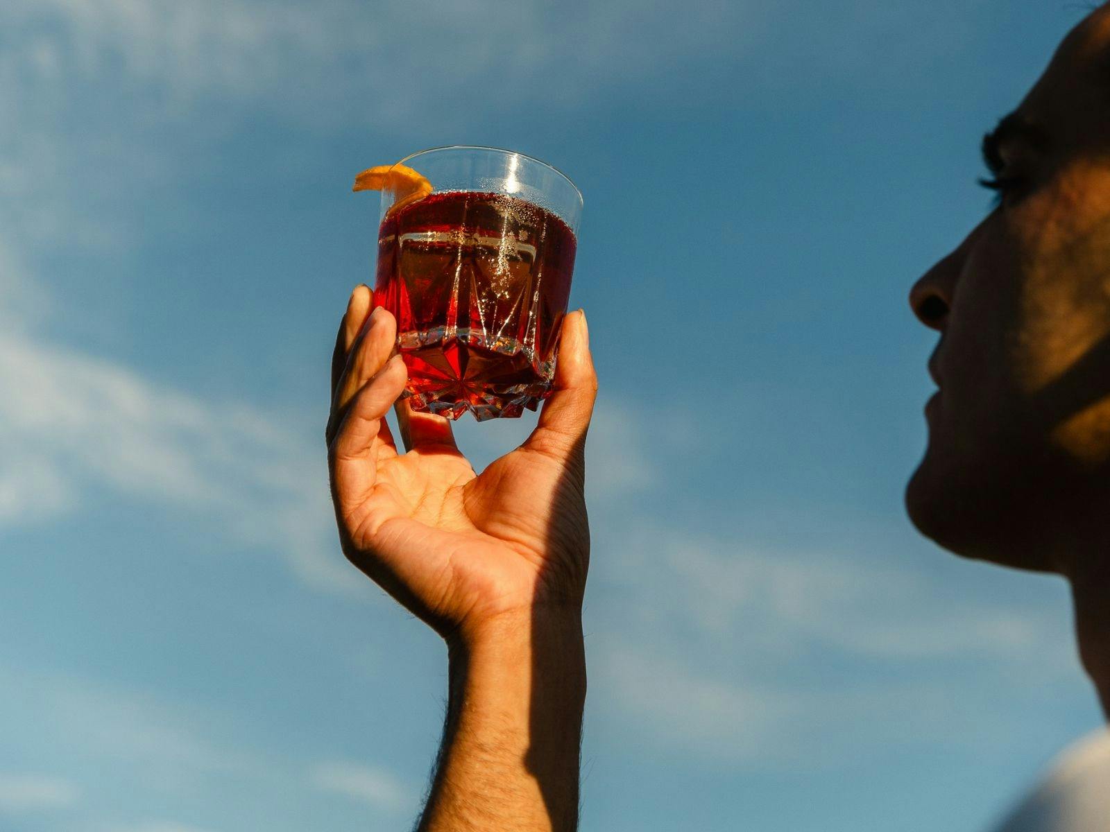 Man holds negroni to the sky