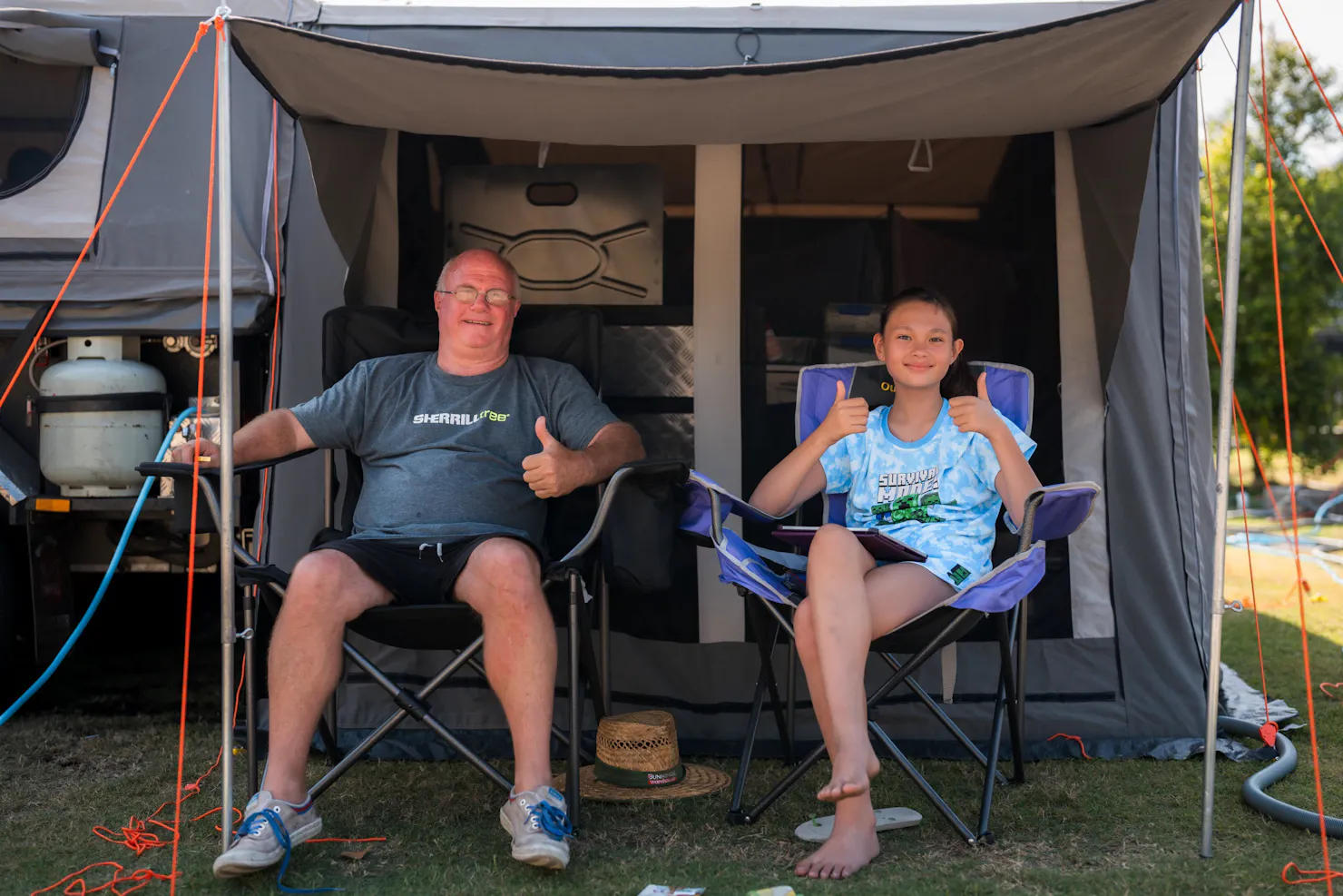 Shot of father and daughter in camp chairs giving thumbs up at Mooloolaba