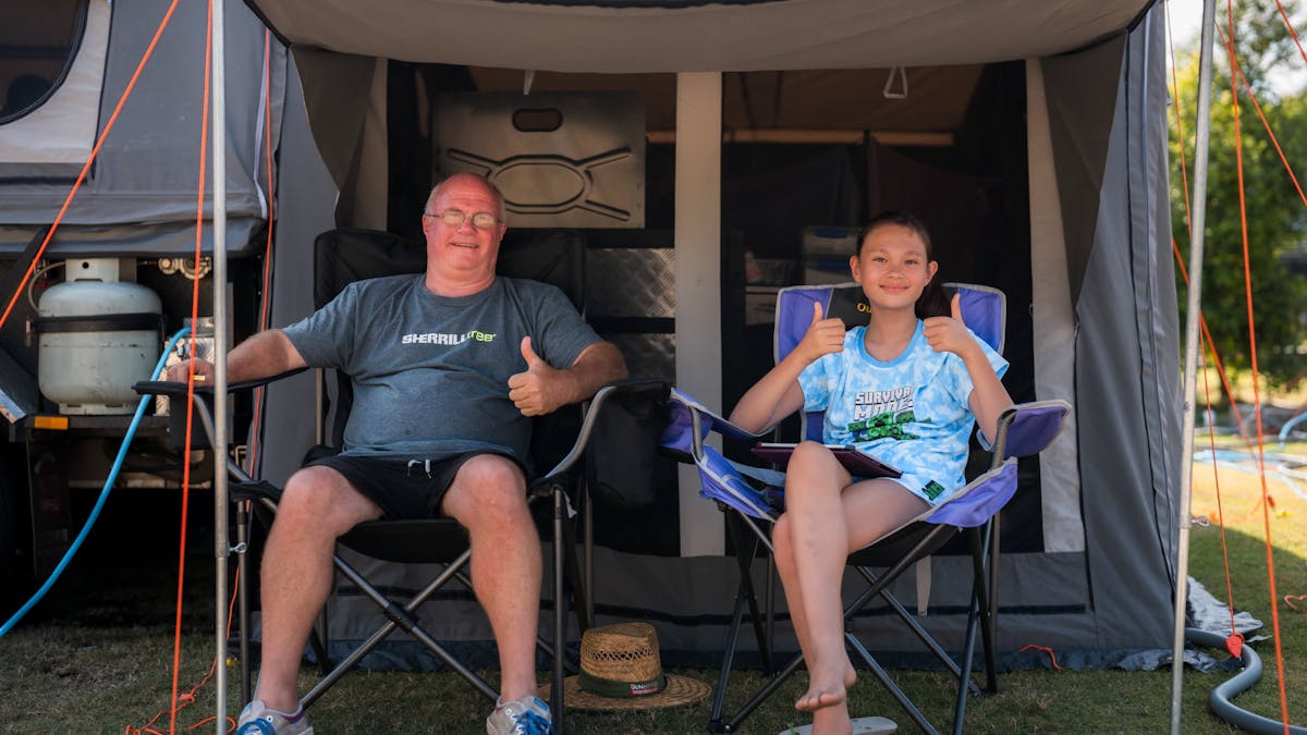 Shot of father and daughter in camp chairs giving thumbs up at Mooloolaba