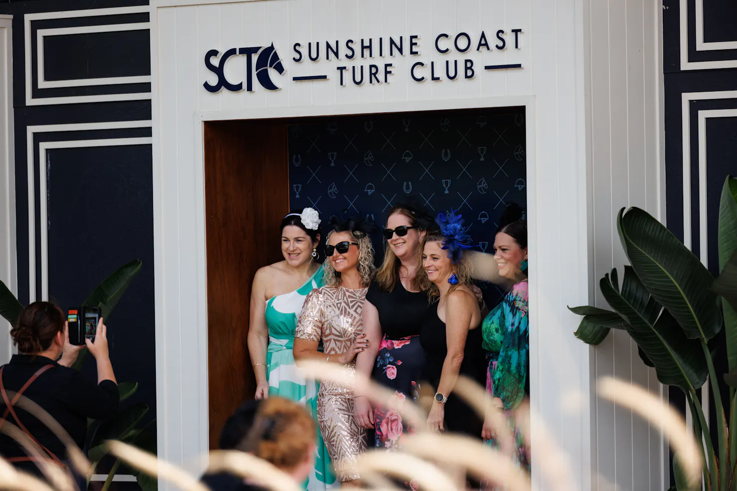 Group of ladies having their photo taken infront of the SCTC Media wall