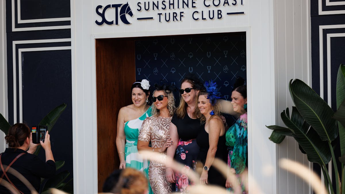 Group of ladies having their photo taken infront of the SCTC Media wall