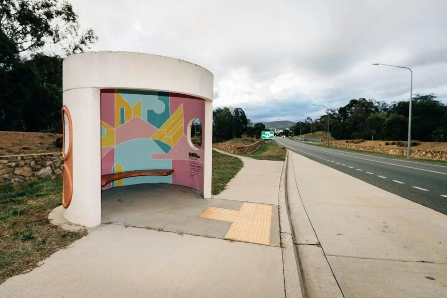 A picture of A Canberra Bus Stop with A painted internal artwork with blue yellow and pink