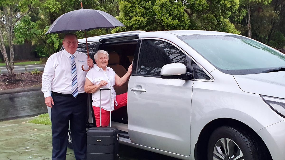 Photo of driver loading passenger into vehicle on a rainy day