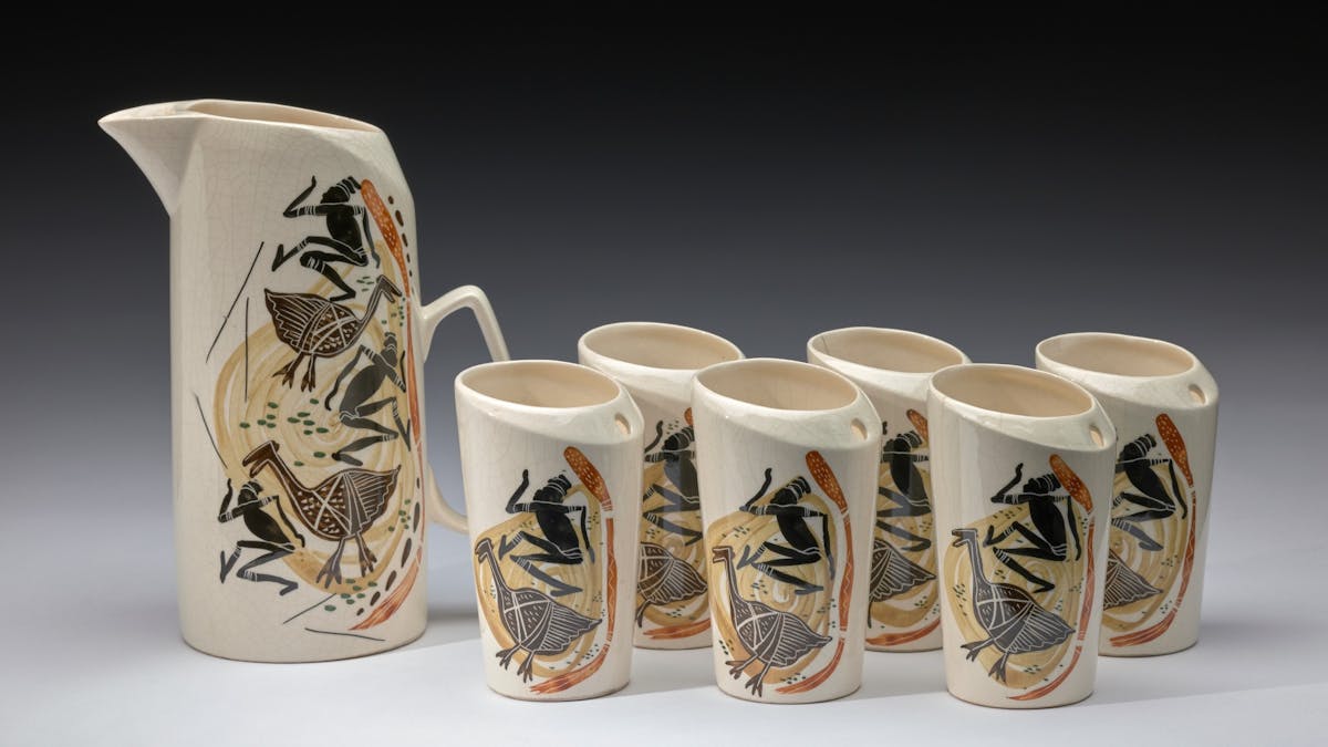 A ceramic cup jug and cup set lined up to display painted detail