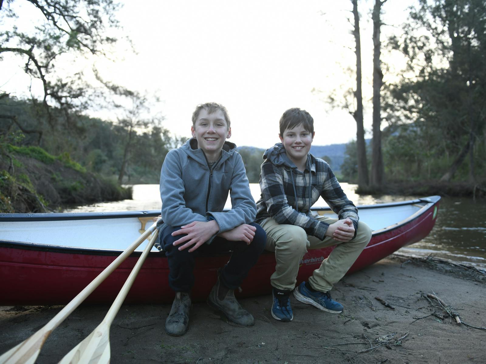 2 boys sitting on a canoe
