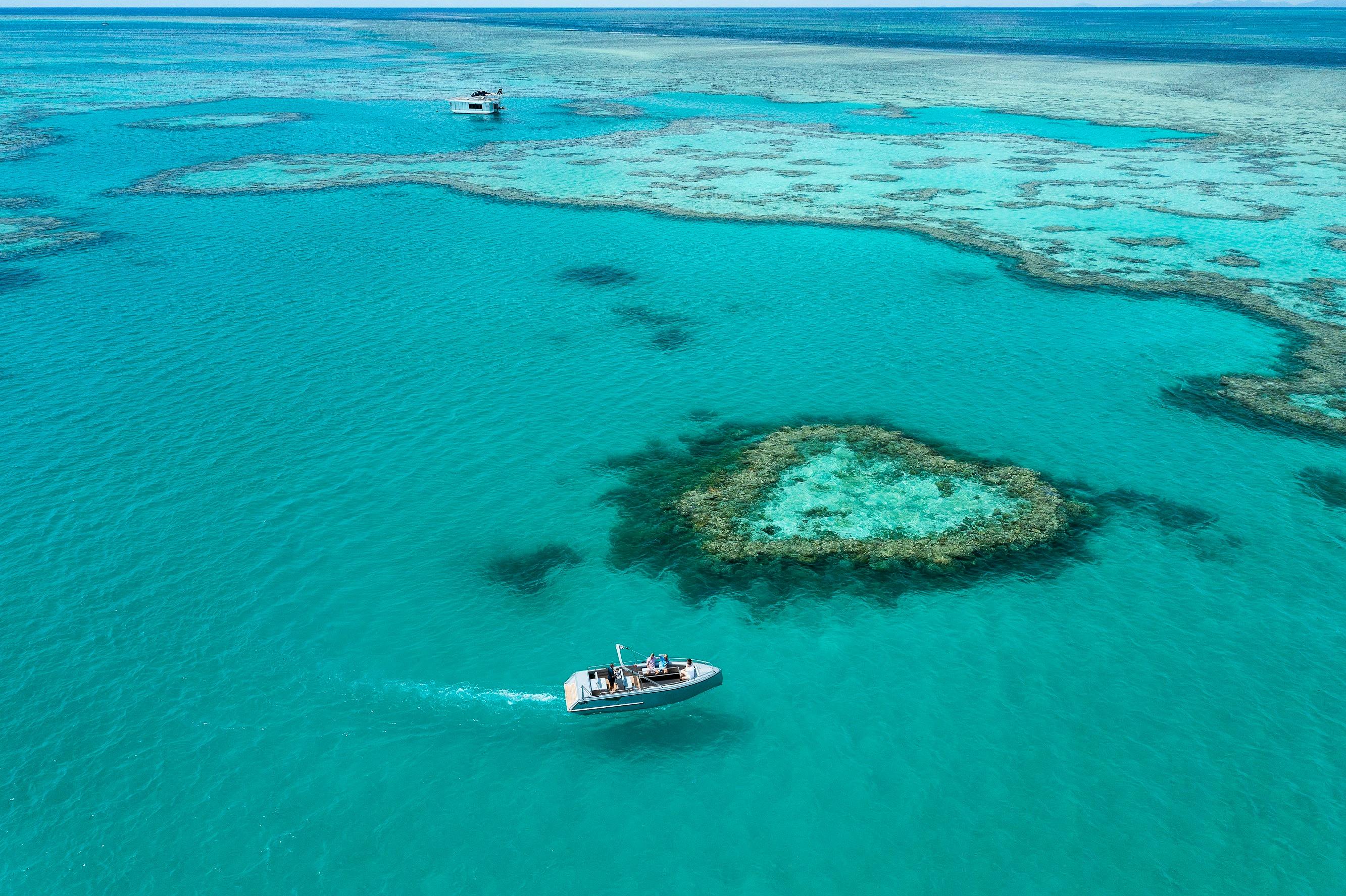 Aerial view showing a boat close to the heart reef and surrounding coral in sea