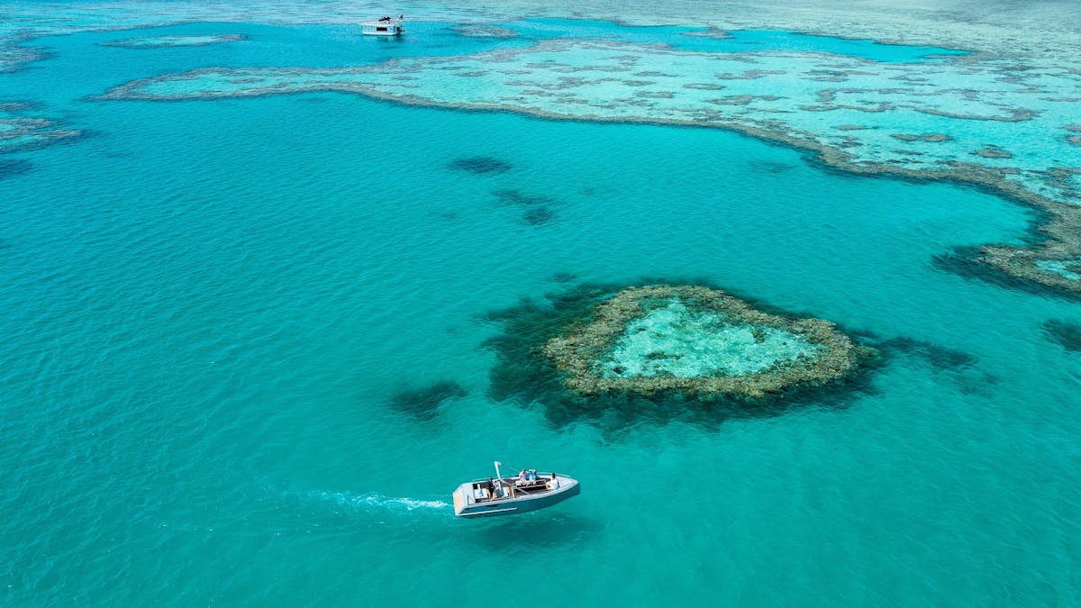 Aerial view showing a boat close to the heart reef and surrounding coral in sea