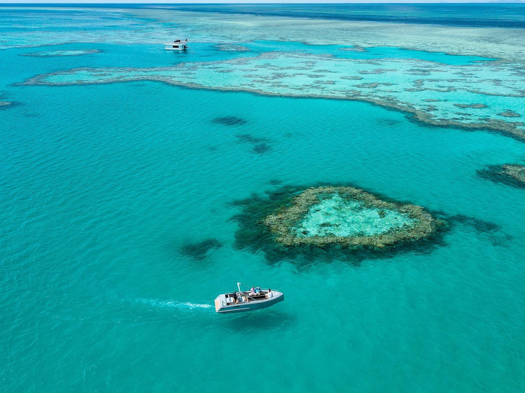 Aerial view showing a boat close to the heart reef and surrounding coral in sea