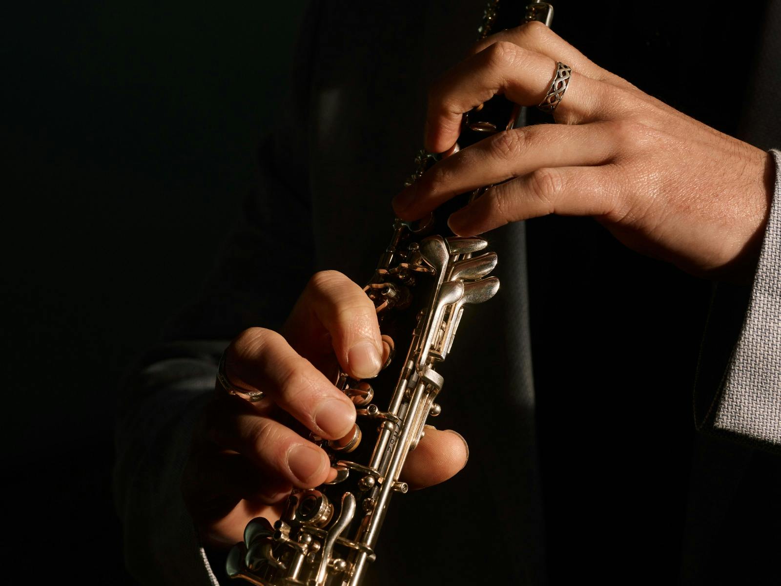 A close up photo of an oboe, with the players' hands pressing keys.