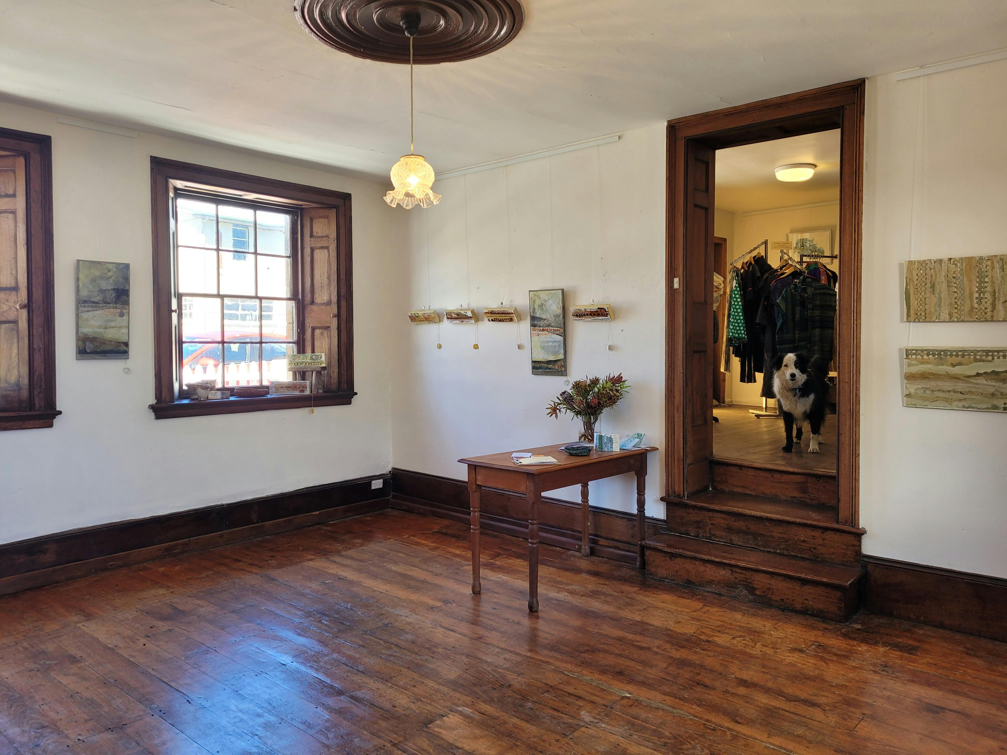 Georgian room built in 1845 used as a gallery with cedar shutters, timber floor & artwork on walls.