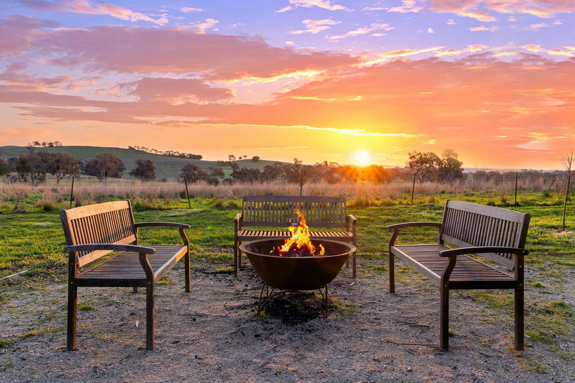 Some outdoor wooden furniture surrounding a fire pit while watching an amazing