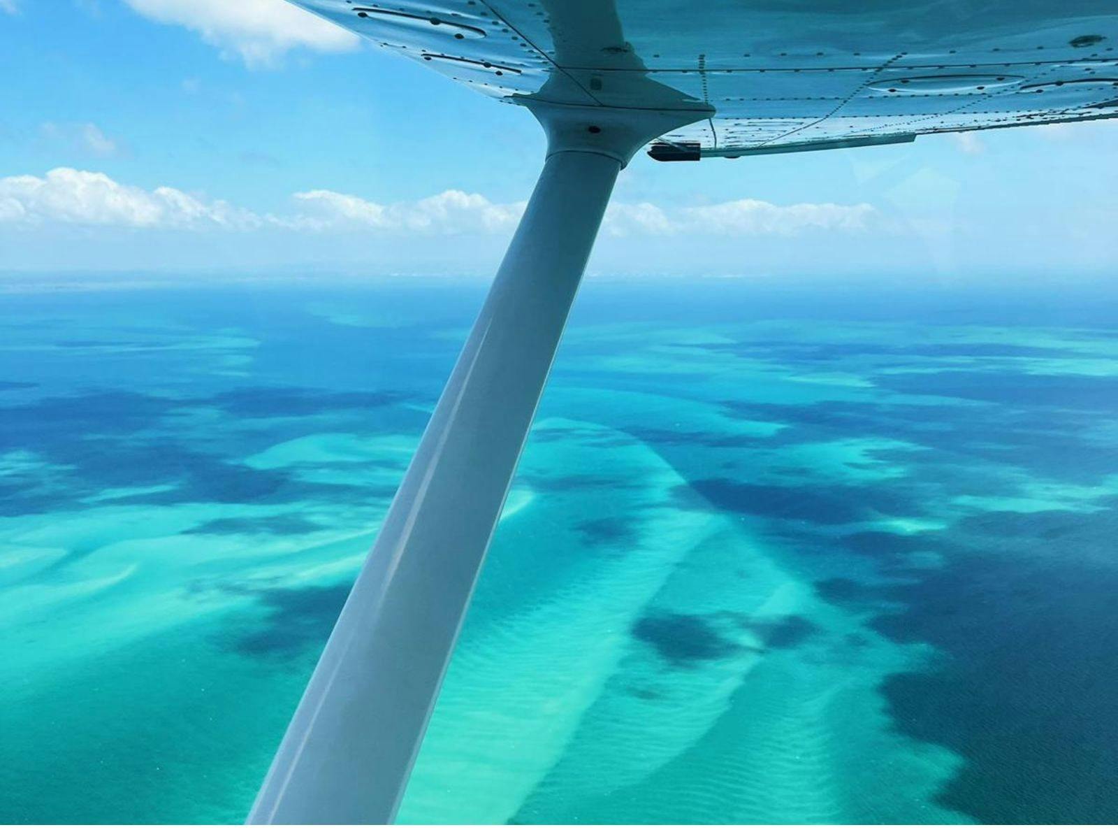 Turquoise blue waters framed by the wing of a plane