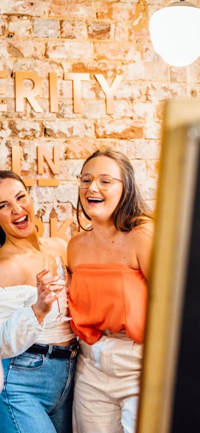 People taking photo in front of Verity Lane Market logo next to flowers