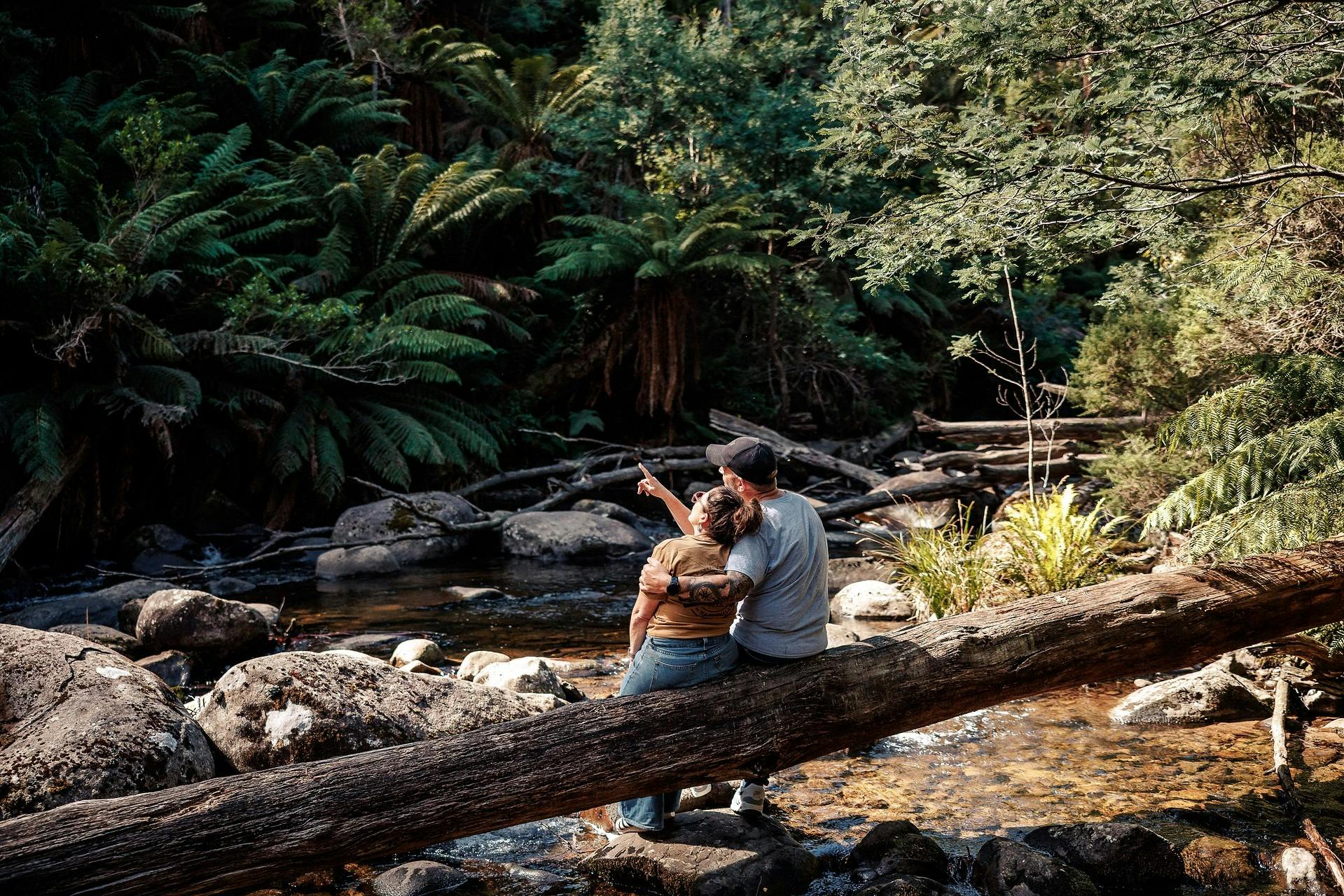 Couple sitting on a large tree trunk at Keppel Falls