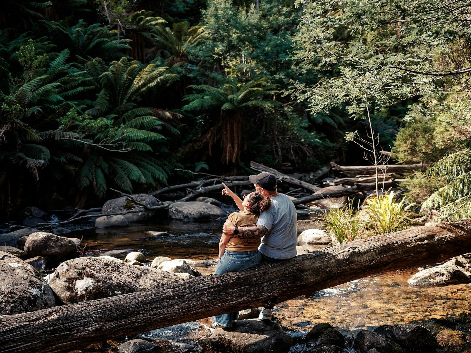 Couple sitting on a large tree trunk at Keppel Falls