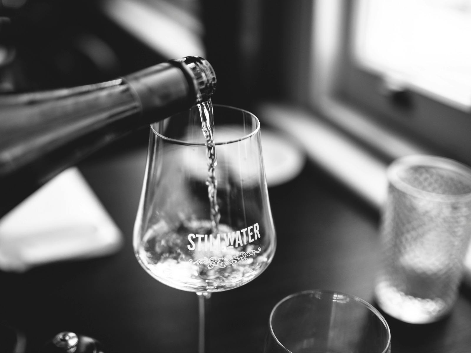 Pouring wine in to a branded Stillwater wine glass at the table.