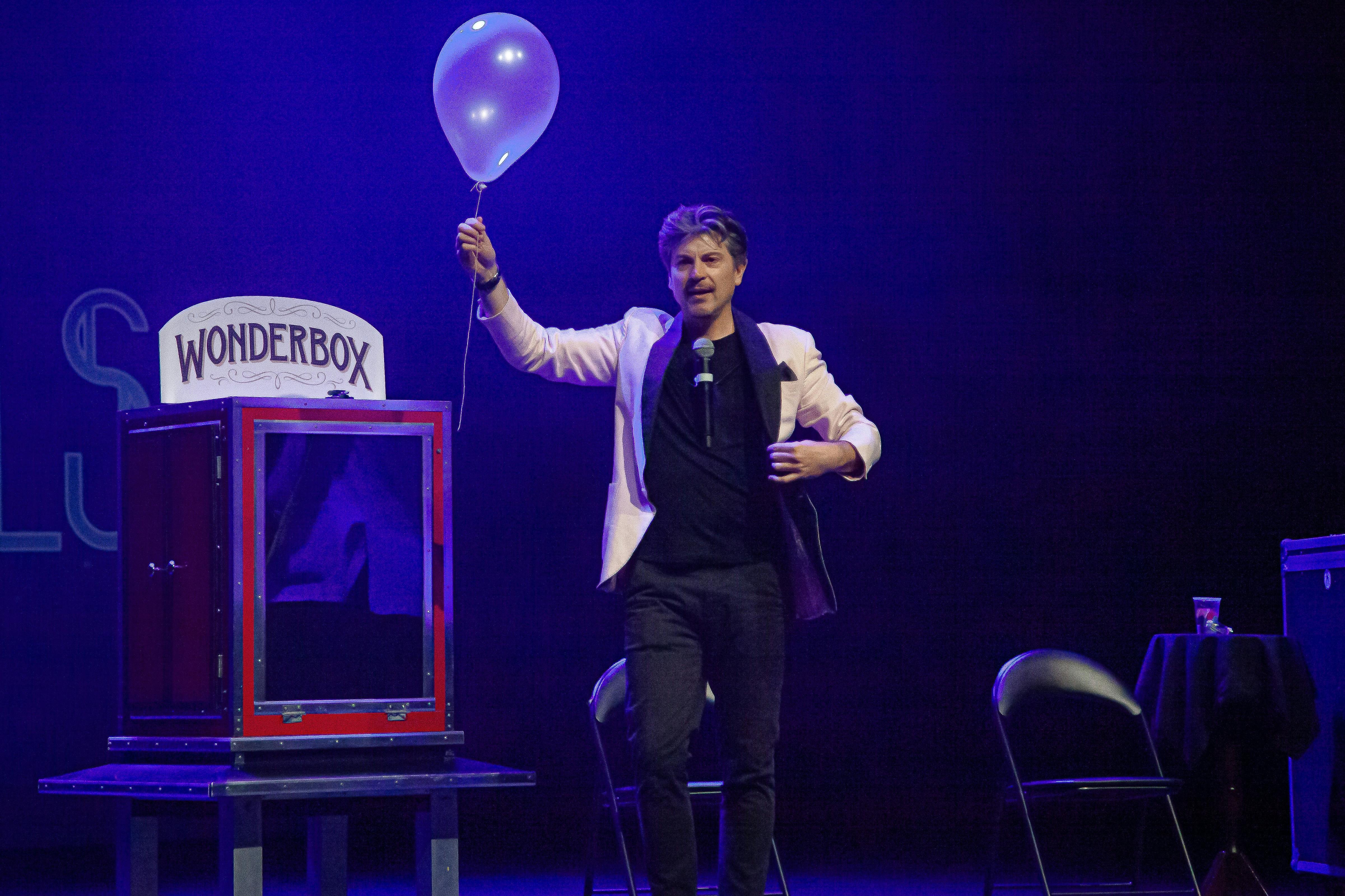 Magician adam mada holding a balloon in front of his invention the Wonderbox.