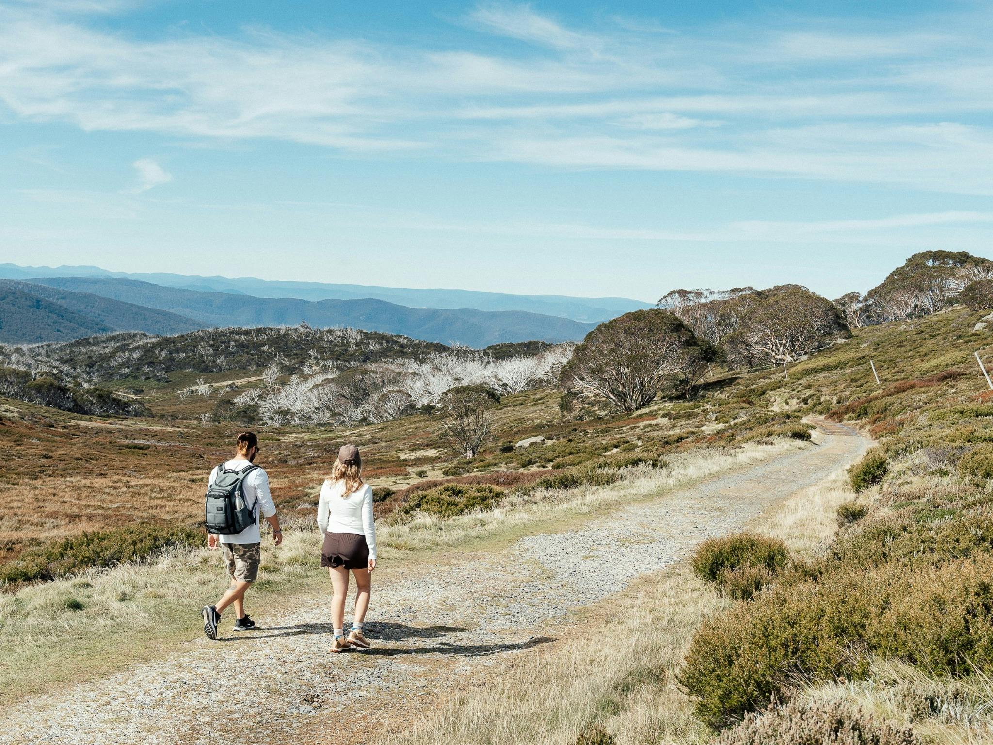 2 people walking with an endless view of mountain background on gravel trail