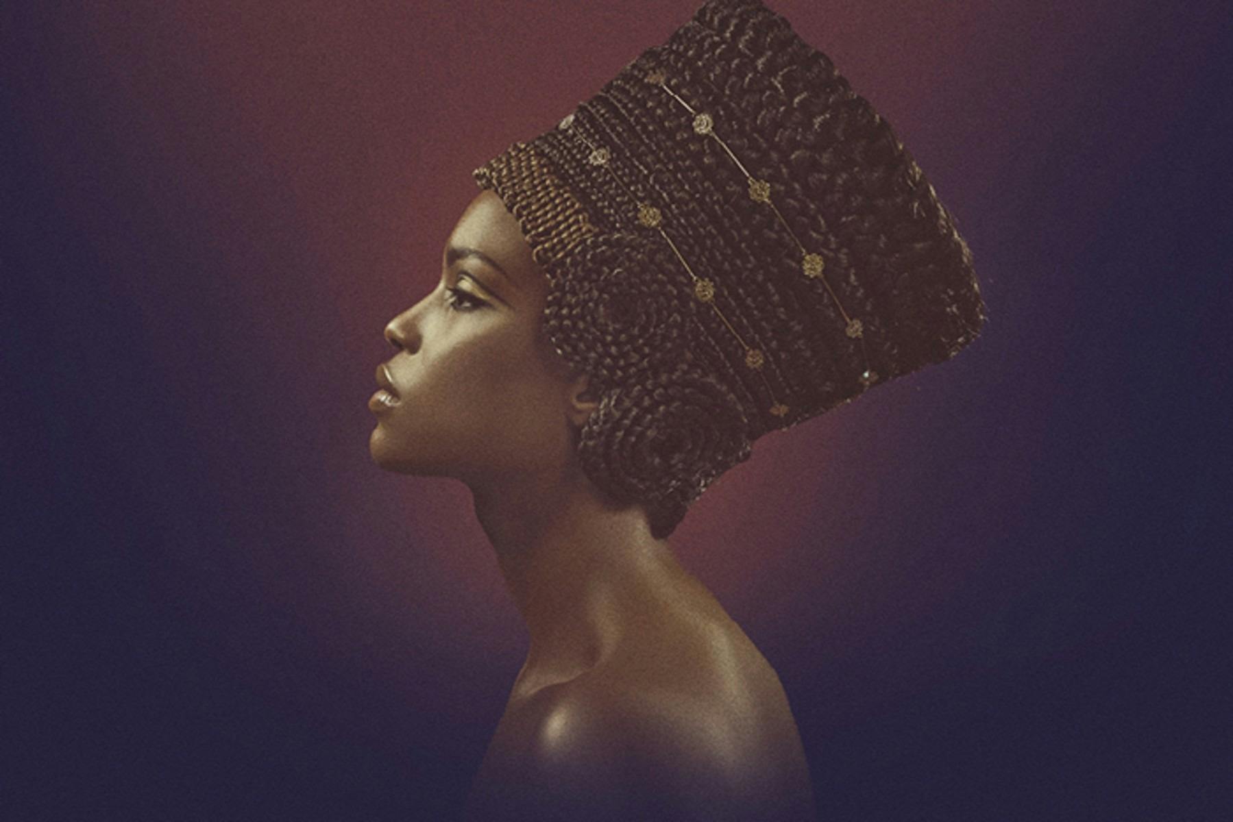 Profile of a woman with an elaborate braided hairstyle adorned with gold accents.