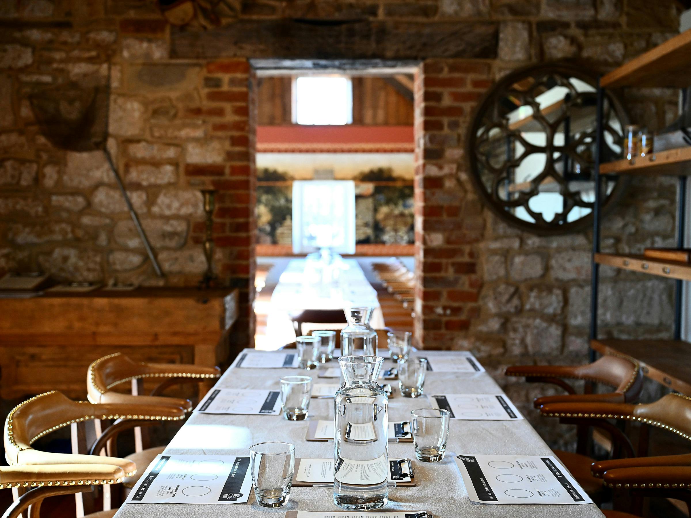 Whisky tasting table set with glasses, water jugs and mats.