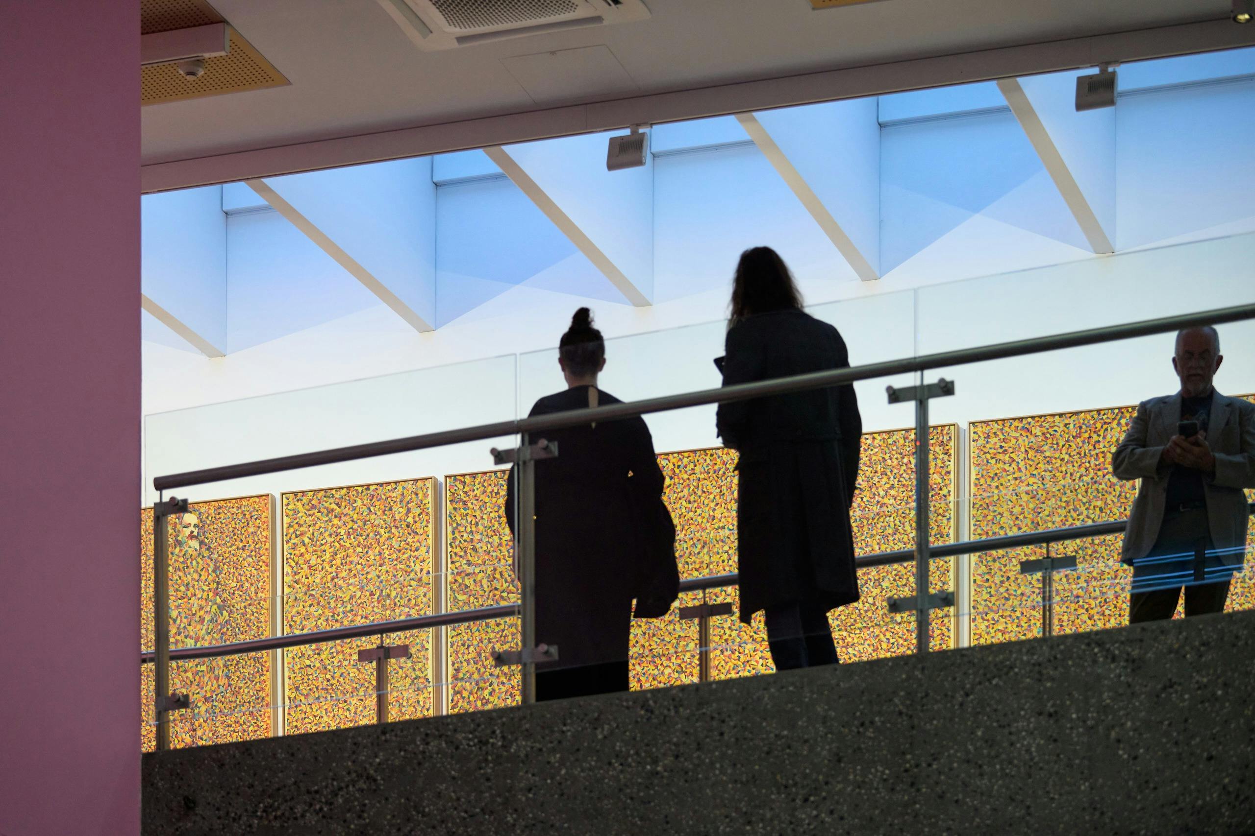 Two people stand on a landing over looking a detail painting