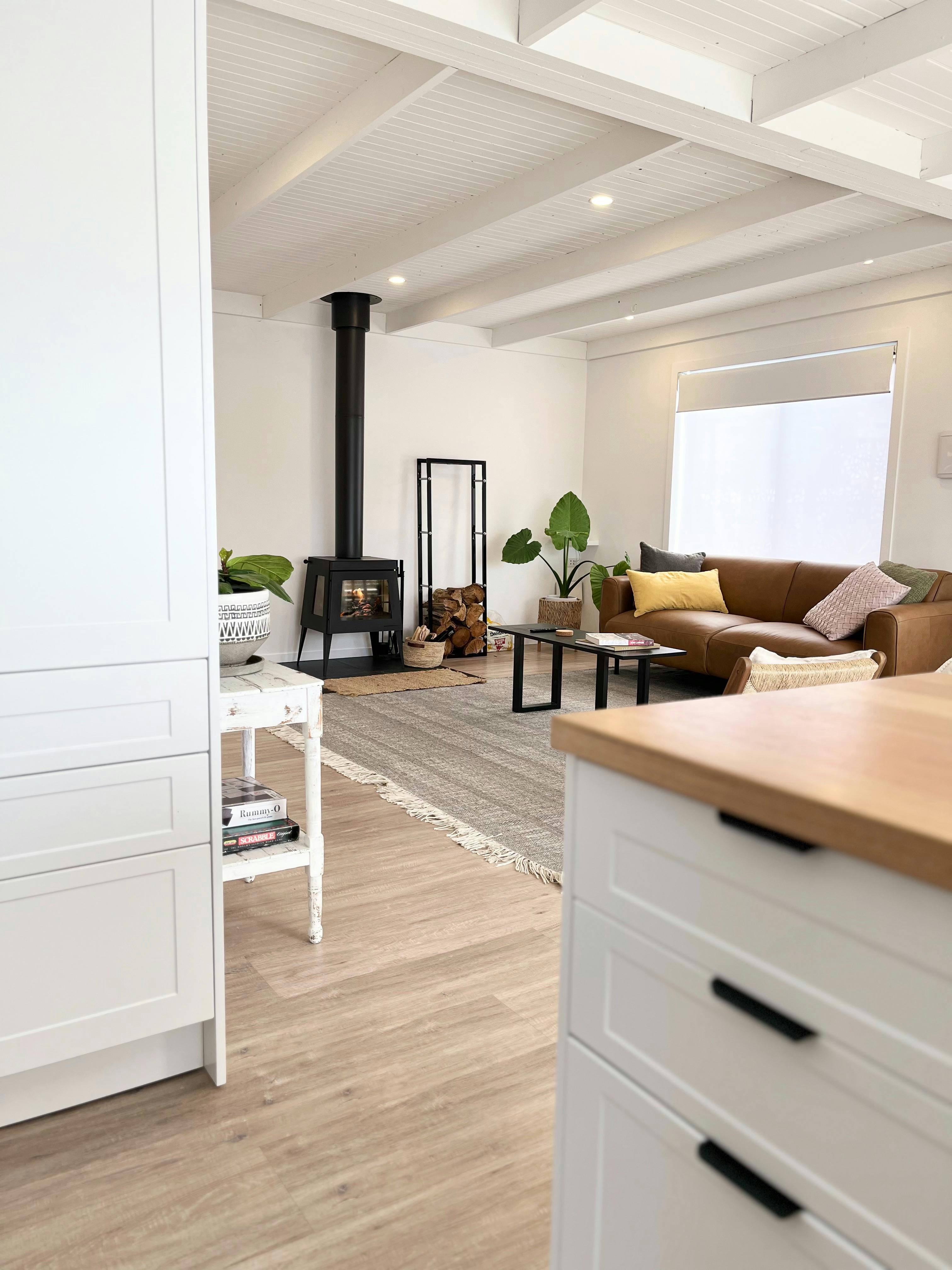 Stylish living area with wood heater, leather sofas and a calm, modern fee