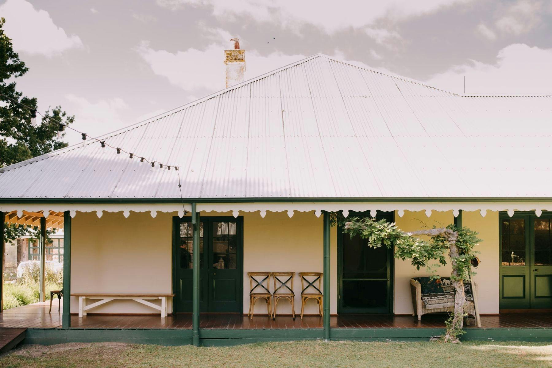 1842 historic homestead verandah with timber chairs and a wisteria creeping along accented eaves