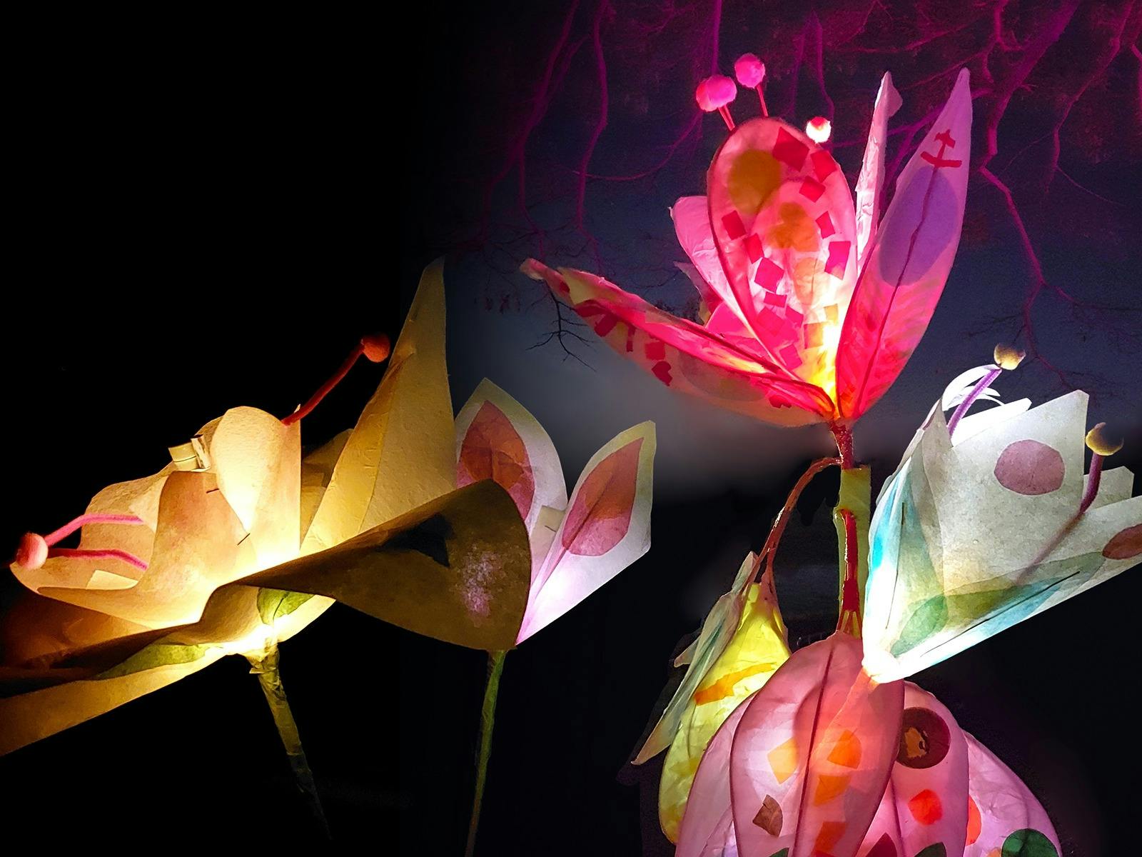 Colourful handmade paper flowers of assorted shapes glow against a dark background aga