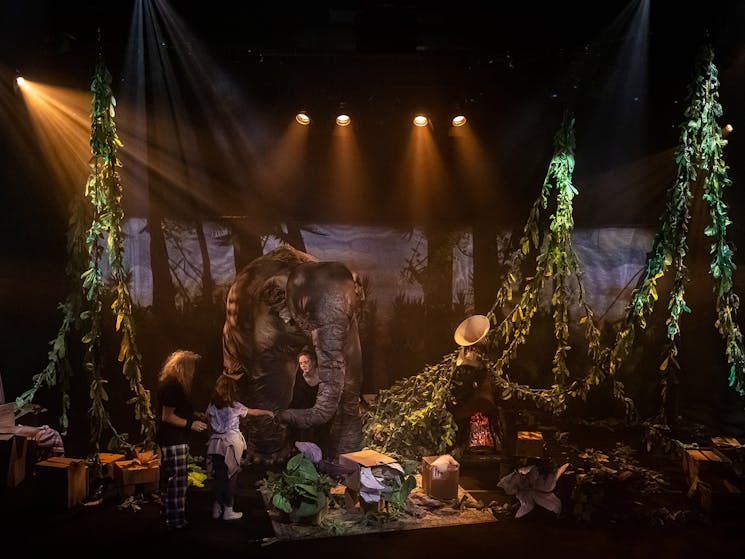 Image of a stage that has been decorated to look like a jungle, with a large elephant puppet.