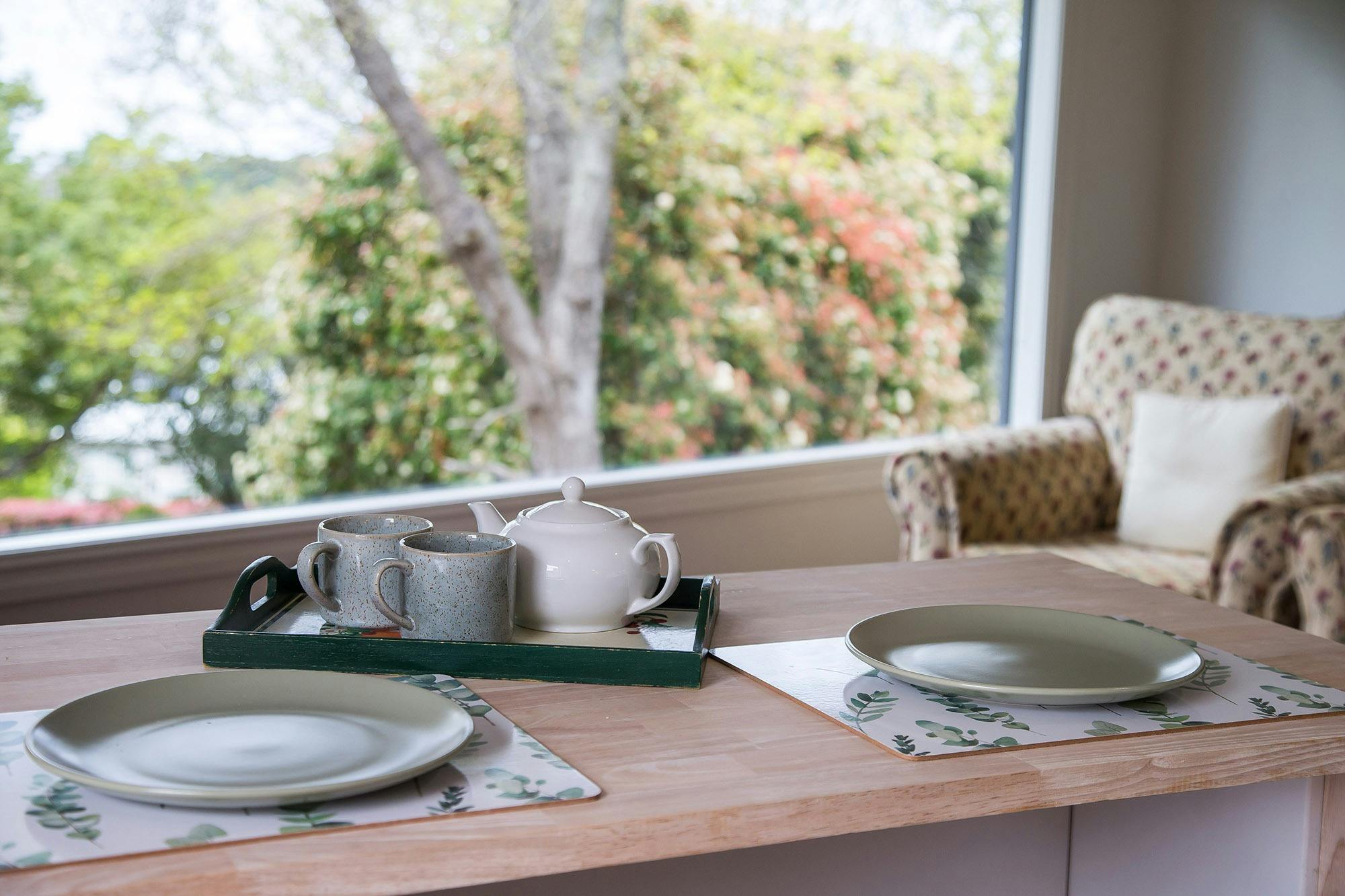 Breakfast bar with crockery setting looking through window to trees