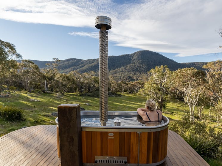 girl soaks in timber hottub with mountain views