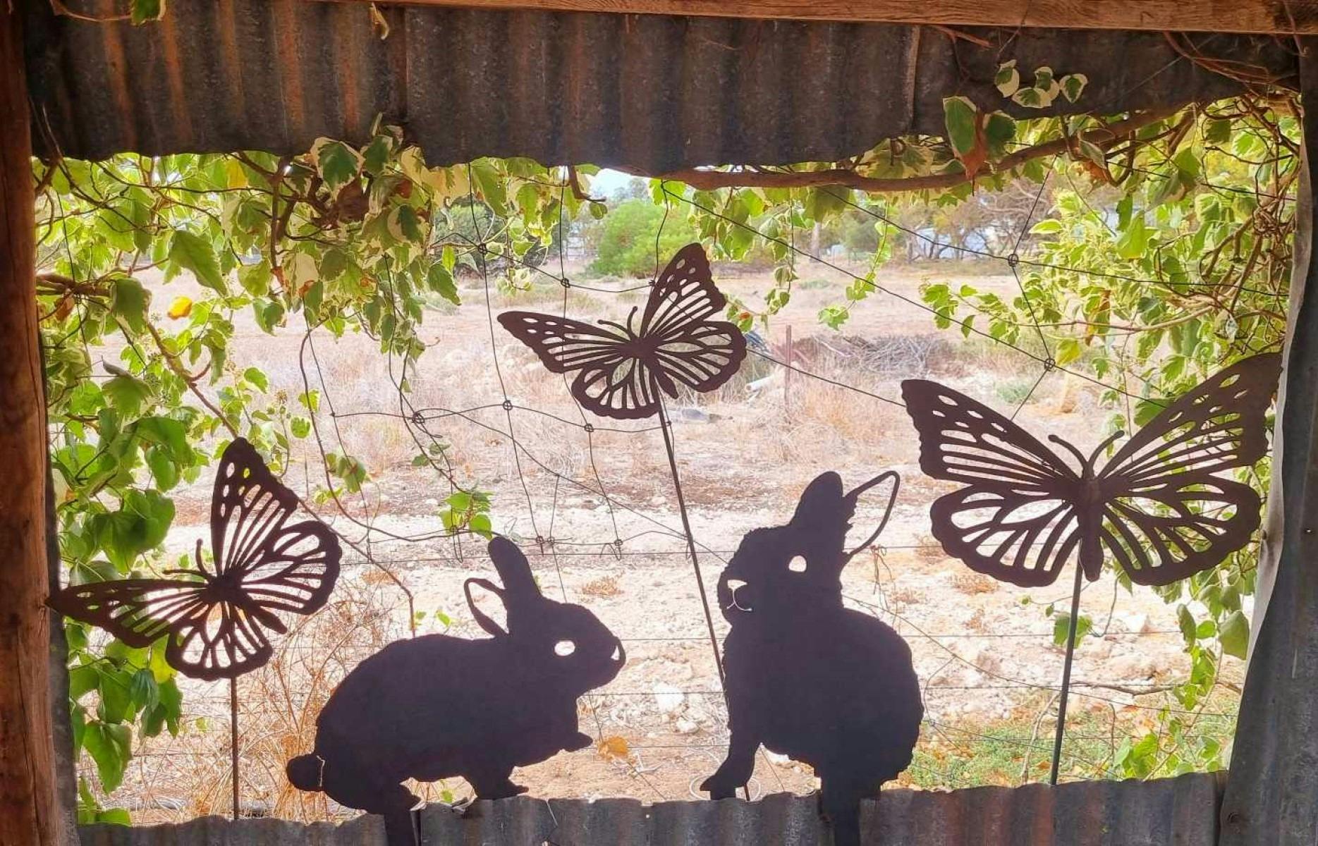 Butterfly and Rabbit Garden stakes in a rustic garden
