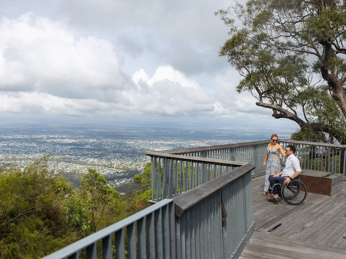 A man, who is in a wheelchair, stands with his wife overlooking a beautiful view of Rockhampton.