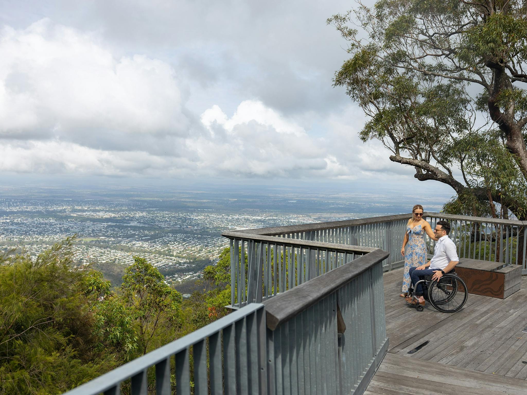 A man, who is in a wheelchair, stands with his wife overlooking a beautiful view of Rockhampton. A man, who is in a wheelchair, stands with his wife overlooking a beautiful view of Rockhampton.