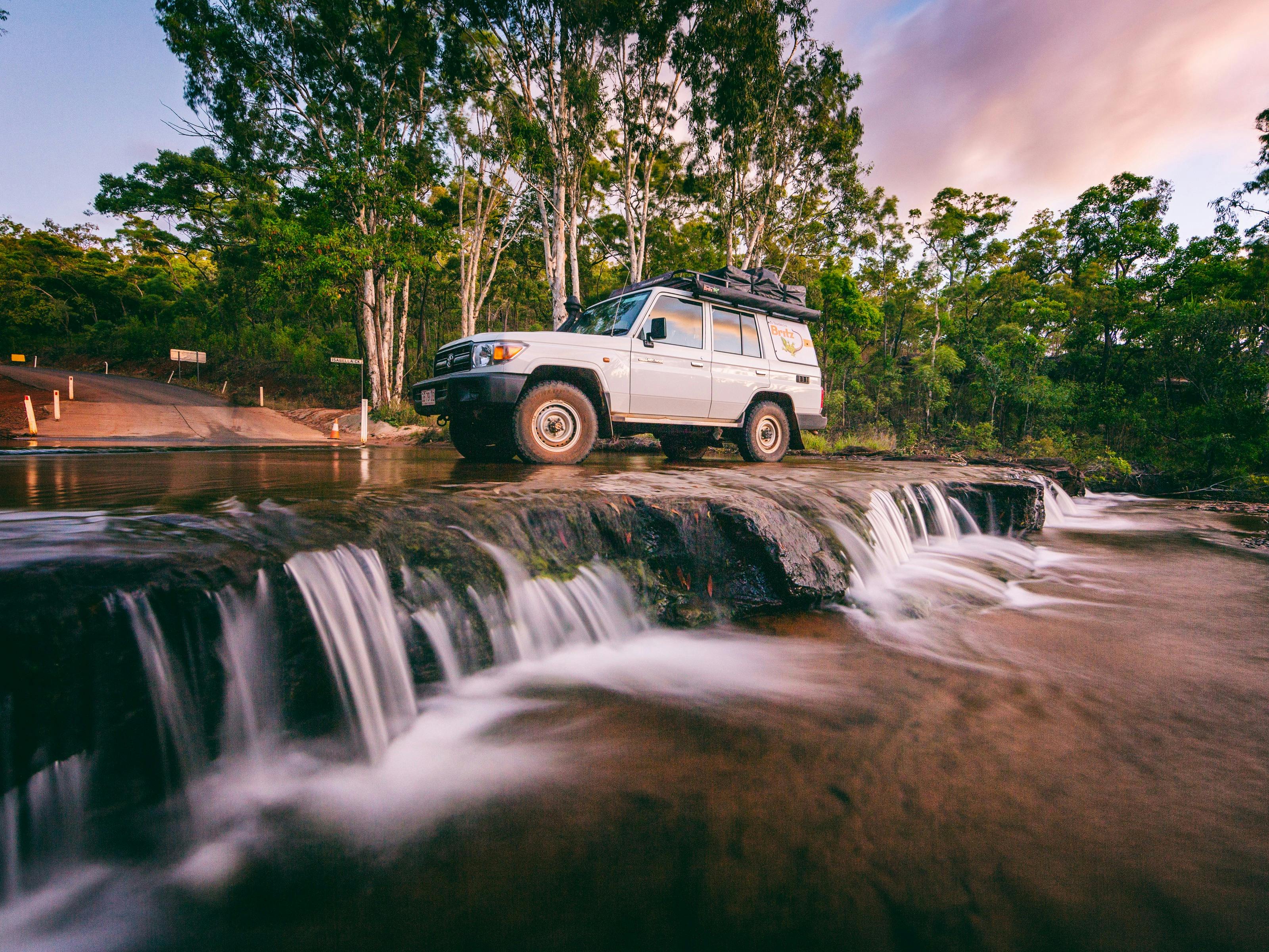 4WD hire car parked in flowing creek water at top of Isabelle Falls.